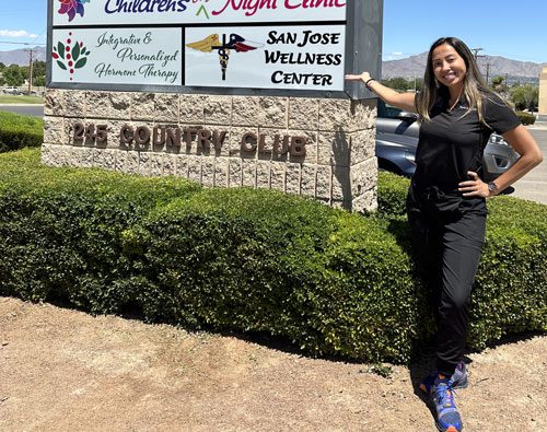 Dr. Mayedel San Jose points at the outdoor sign to San Jose Wellness Center